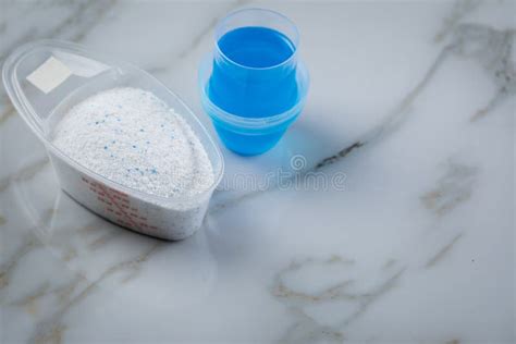 Laundry Detergent Powder And Blue Liquid Gel In Measuring Cup Stock