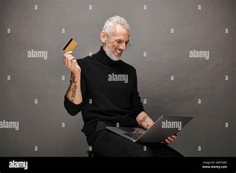 Joyful Attractive Mature Man With Glasses In Turtleneck Holding Credit