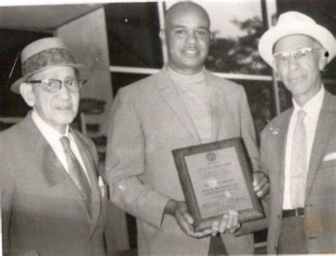 Three Men Standing Next To Each Other In Suits And Ties One Holding An