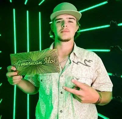 a man holding up an american idol card in front of green neon lights ...