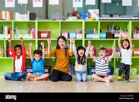 Happy Asian Female Teacher And Mixed Race Kids In Classroom