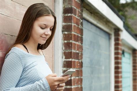 Adolescente Que Texting No Telefone Celular No Ajuste Urbano Foto De