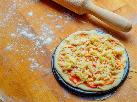 Pizza Base From Dough With Tomato Sauce And Cheese On A Wooden Table