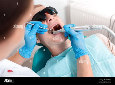 A Female Dentist Examines The Oral Cavity Of The Patient With A Tool