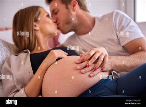 Loving Couple At Home Lying On Bed With Man Touching Pregnant Woman S