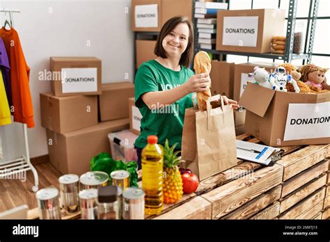 Brunette Woman With Down Syndrome Putting Donated Food In Paper Bag At