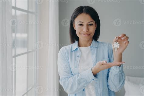 Satisfied hispanic girl holding house keychain in hand. Young woman is