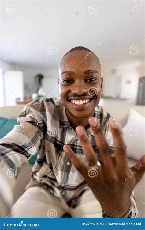 African American Gay Man With Short Hair Showing Wedding Ring While Sitting On Sofa In Living