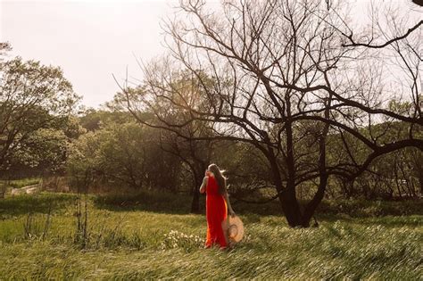 Una Mujer Con Un Vestido Rojo Se Encuentra En Un Campo Con Un Rbol Al