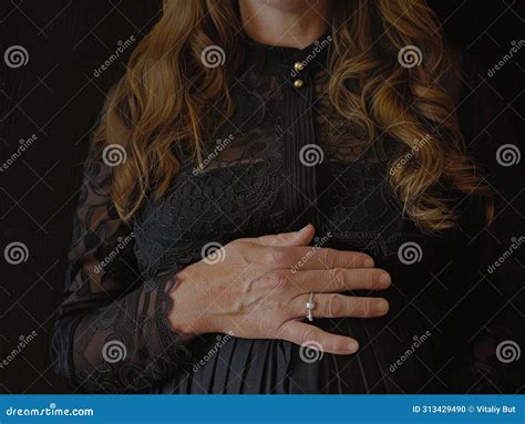 A Pregnant Woman Stands Gracefully In A Black Dress Her Hands