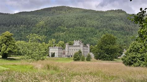 an old castle sits in the middle of a field with trees and mountains ...