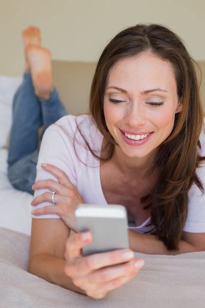 Premium Photo Smiling Woman Using Mobile Phone In Bed