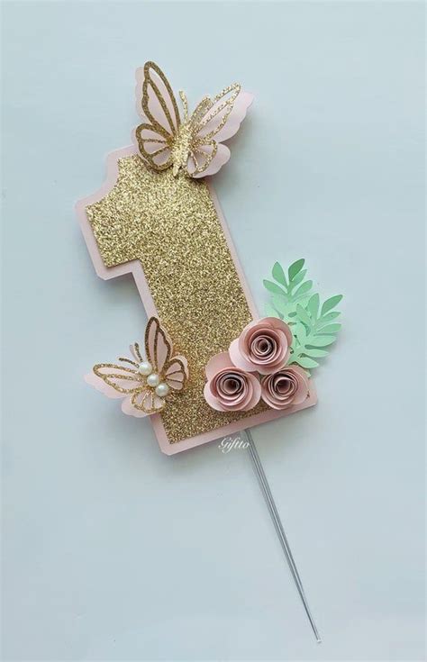 a pink and gold number one cake topper with flowers