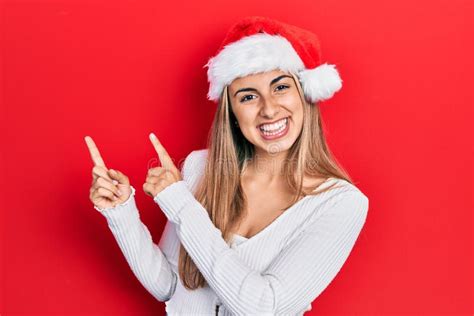 Beautiful Hispanic Woman Wearing Christmas Hat Smiling And Looking At