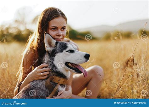 Woman And Her Husky Dog Happily Stroll Through The Grass In The Park