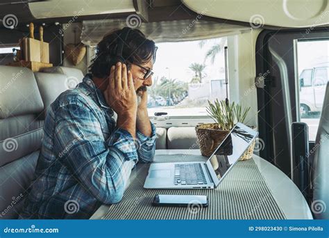 Adult Man Sitting At The Desk Using Laptop Computer And Mobile Phone Connection To Work In