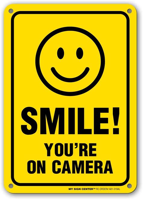 A Yellow Smile Sign With The Words Smile You Re On Camera Written Below It