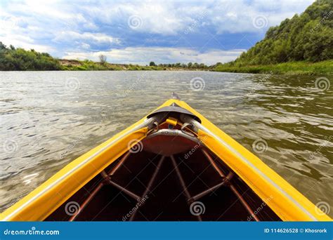 Bow Of Bright Yellow Canoe Paddling On River Surrounded By Fores Stock