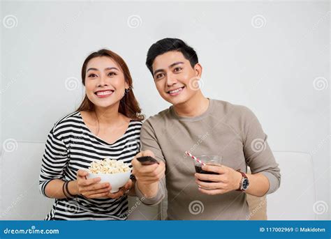 Excited Young Asian Couple Watching Tv And Eating Popcorn Stock Image