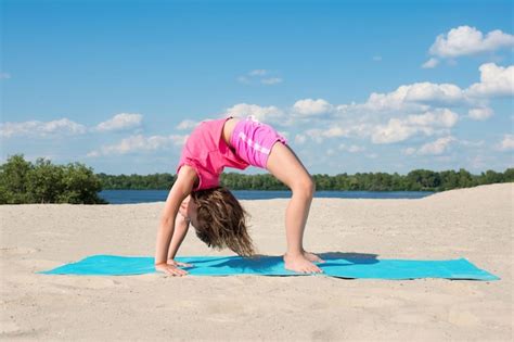 Premium Photo The Little Girl On The Beach Doing Gymnastics On The