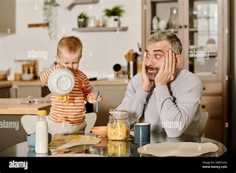 Shocked Mature Man Holding Head In Hands And Looking At His Cute Baby
