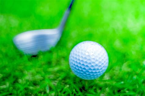 Golf Ball Close Up In Soft Focus At Sunlight With Green Grass Wide