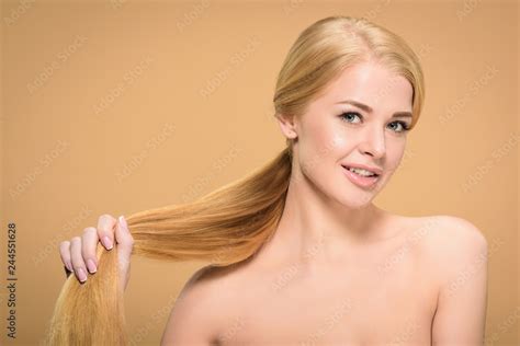 Beautiful Naked Blonde Girl Holding Long Straight Hair And Smiling At Camera Isolated On Beige