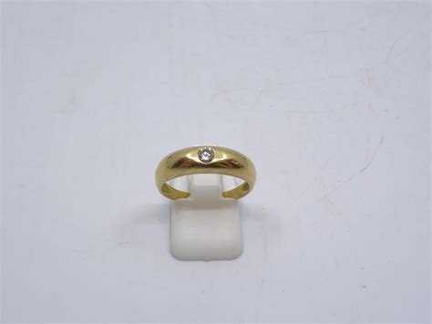 Une bague demi jonc en or jaune 750 ornée en serti clos d un diamant