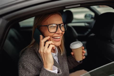 Mulher café falando ao telefone e sentada no banco de trás do táxi