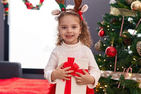 Adorable Blonde Girl Hugging Gift Standing By Christmas Tree At Home Stock Photo Image Of