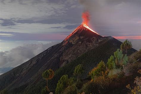 Premium Photo | Aerial view of volcano de fuego erupting covered with trees with smoke and lava ...