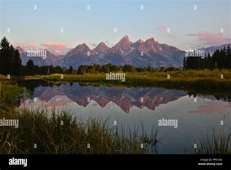 Grand Teton mountains at sunrise/dawn with their reflection in water Stock Photo - Alamy