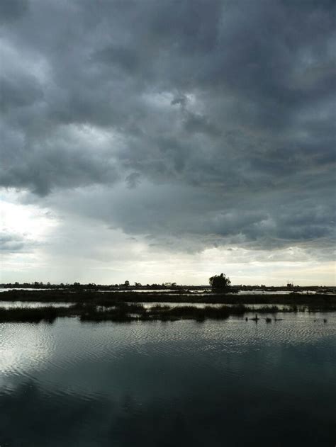 The Sky Is Filled With Dark Clouds And Some Water In Front Of An Area