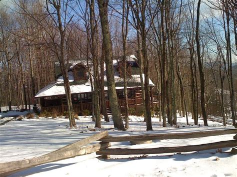 A Cabin In The Woods With Snow On The Ground And Trees Around It Along