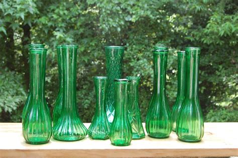 Green Glass Vases Sitting On Top Of A Wooden Table In Front Of Some Trees