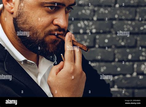 Bearded Man Smoking Cigar Against Black Brick Wall Stock Photo Alamy