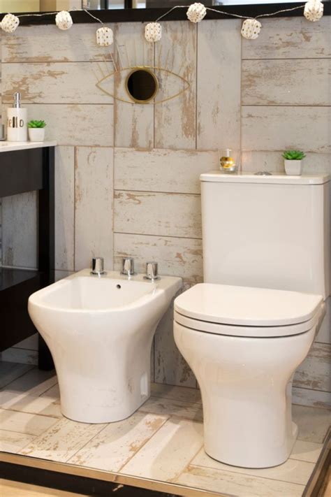 Two White Toilets Sitting Next To Each Other In A Bathroom