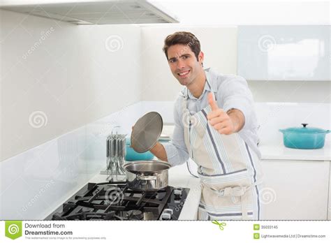 Hombre Joven Sonriente Que Gesticula Los Pulgares Para Arriba En Cocina