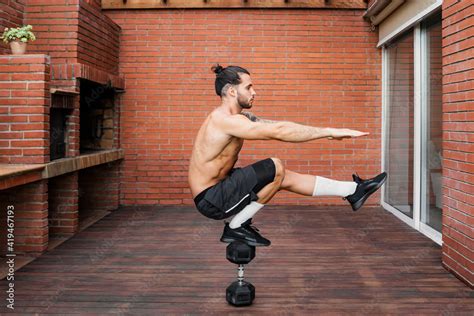 Side View Of Focused Male Athlete With Naked Torso Doing Pistol Squats On Dumbbell And Balancing