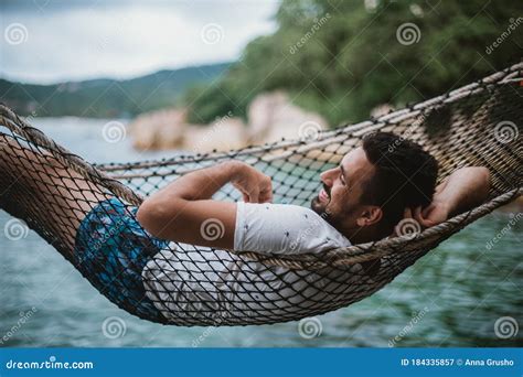 Young Man Lying In A Hammock By The Ocean A Guy Is Resting In A