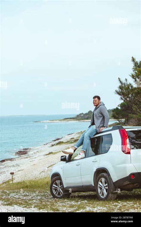 Man Sitting On The Car Roof Enjoying View Of Summer Sea Stock Photo Alamy