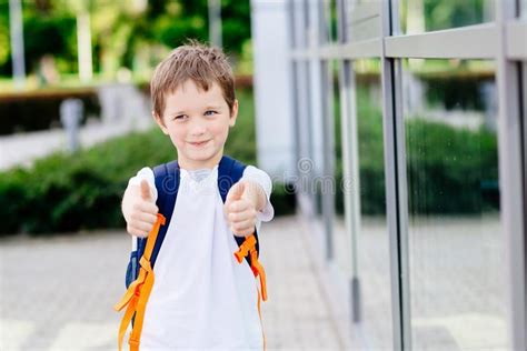 7 Anos Pequenos Felizes Da Estudante Que Mostra Os Polegares Acima Foto