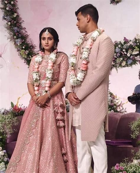 A Man And Woman Standing Next To Each Other In Front Of A Floral