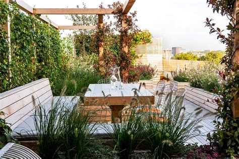 An Outdoor Dining Area With Wooden Benches And Plants