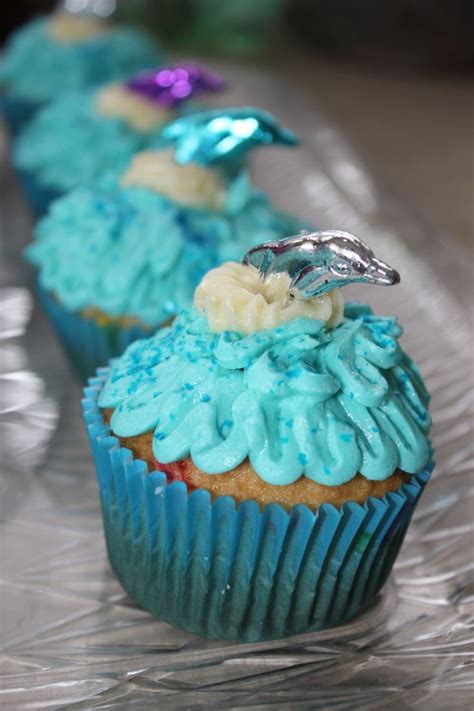 Two Cupcakes With Blue Frosting And Flowers On Them