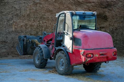 Premium Photo Farmer Unloading Round Bales Of Straw With A Front End