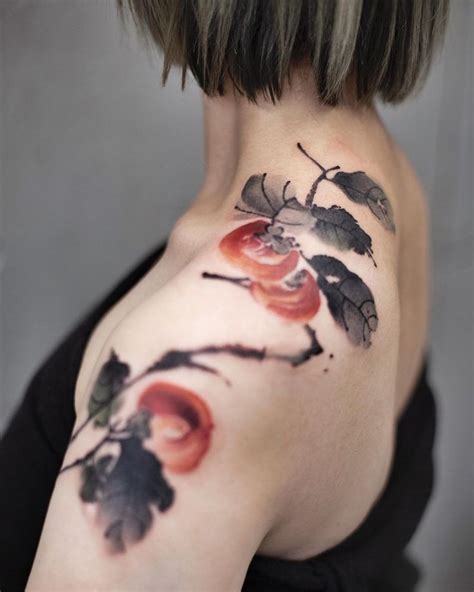 A Woman S Back Shoulder Tattoo With Flowers And Leaves Painted On Her