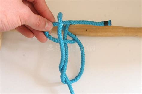 A Person Is Tying A Blue Rope With A Wooden Stick