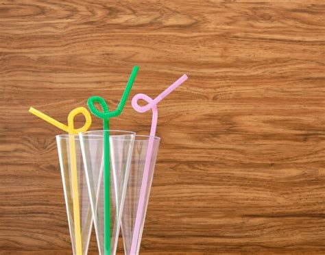 Premium Photo | Plastic glasses for festive drinks with colored curved straws stand on the table ...