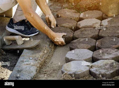 Hands Of Workman Make It Fit And To Place Stone Pavers In A Row